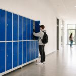 Taquillas metálicas azules para colegios y universidades instaladas en un pasillo educativo moderno con estudiantes.
