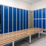 Vestuarios profesionales con taquillas metálicas azules y bancos de madera para empresas, centros deportivos e instalaciones colectivas.
